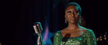 Movie still from “Bad Times at the El Royale” (2018), directed by Drew Goddard – A woman standing next to a microphone on a stage; Close Up shot, Over the shoulder angle