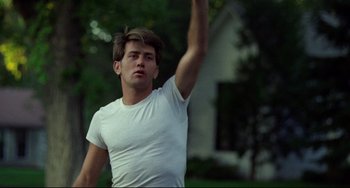 Movie still from “Badlands” (1973), directed by Terrence Malick – A man in a white t - shirt throws a frisbee; Medium shot, Low angle