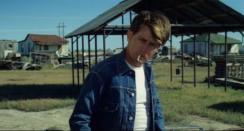 Movie still from “Badlands” (1973), directed by Terrence Malick – A young man smoking a cigarette while wearing a jean jacket; Close Up shot, Over the shoulder angle