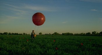 Movie still from “Badlands” (1973), directed by Terrence Malick – A man in a field with a large red balloon; Extreme Wide shot, Low angle