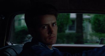 Movie still from “Badlands” (1973), directed by Terrence Malick – A man sitting in the back seat of a car; Close Up shot, Over the shoulder angle