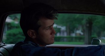 Movie still from “Badlands” (1973), directed by Terrence Malick – A man sitting in the passenger seat of a car looking out the window; Close Up shot, Over the shoulder angle