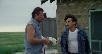Movie still from “Badlands” (1973), directed by Terrence Malick – Two men standing next to each other in a field; Medium shot, Over the shoulder angle