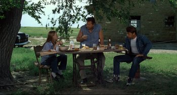 Movie still from “Badlands” (1973), directed by Terrence Malick – Three people sitting at a table eating food; Wide shot, Over the shoulder angle