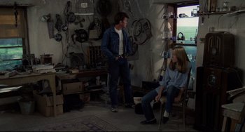 Movie still from “Badlands” (1973), directed by Terrence Malick – A man and a woman sitting in a garage; Wide shot, Over the shoulder angle