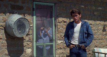 Movie still from “Badlands” (1973), directed by Terrence Malick – A man standing in front of a window taking a picture of himself; Medium shot, Over the shoulder angle