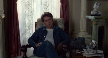 Movie still from “Badlands” (1973), directed by Terrence Malick – A man sitting in a chair in front of a window; Medium shot, Over the shoulder angle