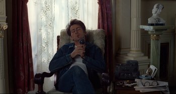 Movie still from “Badlands” (1973), directed by Terrence Malick – A man sitting in a chair holding a camera; Medium shot, Low angle