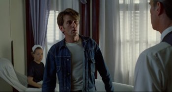 Movie still from “Badlands” (1973), directed by Terrence Malick – A man standing in front of a window in a room; Medium shot, Over the shoulder angle