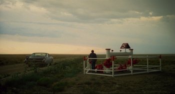 Movie still from “Badlands” (1973), directed by Terrence Malick – A man standing in a field next to a car; Extreme Wide shot, Over the shoulder angle