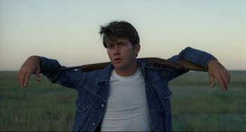 Movie still from “Badlands” (1973), directed by Terrence Malick – A young man holding a baseball bat over his shoulder; Medium shot, Over the shoulder angle