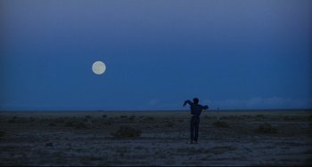 Movie still from “Badlands” (1973), directed by Terrence Malick – A man standing in the middle of a field flying a kite; Extreme Wide shot, Low angle