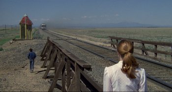Movie still from “Badlands” (1973), directed by Terrence Malick – A woman standing on the side of a train track; Wide shot, Over the shoulder angle