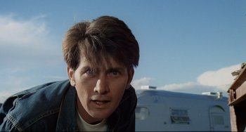 Movie still from “Badlands” (1973), directed by Terrence Malick – A young man with short brown hair is looking at the camera; Close Up shot, Low angle