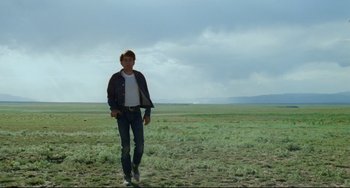 Movie still from “Badlands” (1973), directed by Terrence Malick – A man in a field with a sky in the background; Wide shot, Low angle
