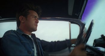 Movie still from “Badlands” (1973), directed by Terrence Malick – A man driving a car in the middle of the day; Close Up shot, Low angle