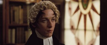 Movie still from “Becoming Jane” (2007), directed by Julian Jarrold – A man in a wig and wig stands in front of a window; Close Up shot, High angle