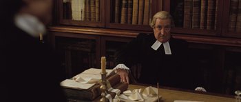 Movie still from “Becoming Jane” (2007), directed by Julian Jarrold – An old man sitting at a table in front of books; Medium shot, High angle
