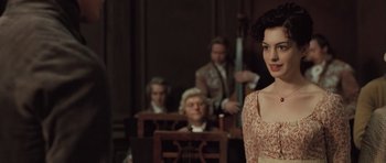 Movie still from “Becoming Jane” (2007), directed by Julian Jarrold – A woman standing in front of a group of people; Medium shot, Over the shoulder angle