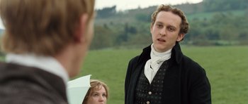Movie still from “Becoming Jane” (2007), directed by Julian Jarrold – A man in a black jacket is standing next to a woman in a white dress; Close Up shot, Over the shoulder angle