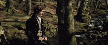 Movie still from “Becoming Jane” (2007), directed by Julian Jarrold – A young man sitting next to a tree in the woods; Medium shot, Over the shoulder angle