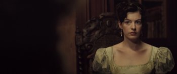Movie still from “Becoming Jane” (2007), directed by Julian Jarrold – A woman sitting in front of an ornate wooden chair; Close Up shot, Over the shoulder angle