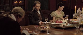 Movie still from “Becoming Jane” (2007), directed by Julian Jarrold – A man sitting at a table with a plate of food; Medium shot, Over the shoulder angle
