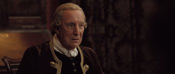 Movie still from “Becoming Jane” (2007), directed by Julian Jarrold – An old man with a long hair and a beard; Close Up shot, Over the shoulder angle