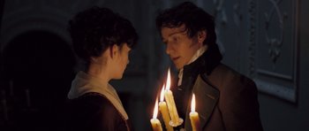 Movie still from “Becoming Jane” (2007), directed by Julian Jarrold – A man and a woman looking at each other with lit candles in front of them; Medium shot, Over the shoulder angle
