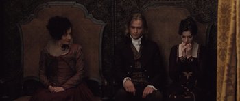 Movie still from “Becoming Jane” (2007), directed by Julian Jarrold – A man and two women sitting on a couch; Medium shot, High angle