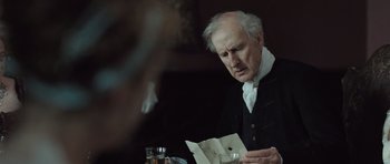 Movie still from “Becoming Jane” (2007), directed by Julian Jarrold – An older man sitting at a table looking at a piece of paper in front of him; Close Up shot, Over the shoulder angle