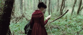 Movie still from “Becoming Jane” (2007), directed by Julian Jarrold – A woman in a red dress is reading a book in the woods; Medium shot, Over the shoulder angle