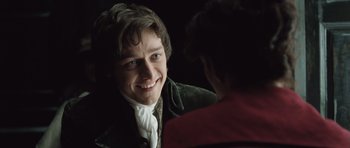 Movie still from “Becoming Jane” (2007), directed by Julian Jarrold – A man in a green jacket smiling at another man; Close Up shot, Over the shoulder angle