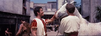 Movie still from “Ben-Hur” (1959), directed by William Wyler – A man in roman garb petting a white horse; Medium shot, Over the shoulder angle