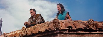 Movie still from “Ben-Hur” (1959), directed by William Wyler – A woman and a man are sitting on a building; Medium shot, Low angle