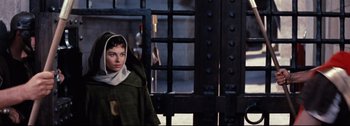 Movie still from “Ben-Hur” (1959), directed by William Wyler – A woman standing in front of a metal gate; Medium shot, High angle