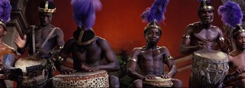 Movie still from “Ben-Hur” (1959), directed by William Wyler – A couple of men sitting next to each other on drums; Medium shot, High angle