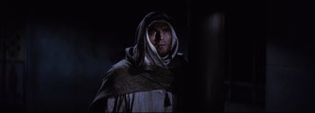 Movie still from “Ben-Hur” (1959), directed by William Wyler – A man wearing a robe and a hood standing in a dark room; Medium shot, Low angle