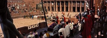 Movie still from “Ben-Hur” (1959), directed by William Wyler – A group of people in costume on a stage in front of a building; Extreme Wide shot, High angle