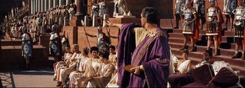 Movie still from “Ben-Hur” (1959), directed by William Wyler – A man dressed as a roman emperor stands in front of a group of people; Wide shot, Over the shoulder angle