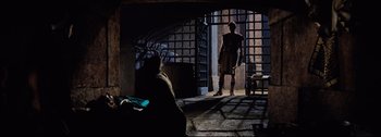 Movie still from “Ben-Hur” (1959), directed by William Wyler – A man standing in front of a woman in front of an open gate; Wide shot, Low angle