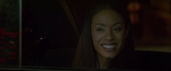 Movie still from “Collateral” (2004), directed by Michael Mann – A woman smiling for the camera in the dark; Close Up shot, Over the shoulder angle