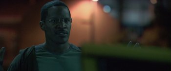 Movie still from “Collateral” (2004), directed by Michael Mann – A person wearing glasses and a green shirt; Close Up shot, Over the shoulder angle