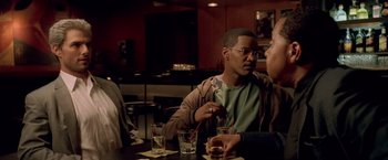 Movie still from “Collateral” (2004), directed by Michael Mann – A man sitting at a table in front of two other men; Medium shot, Over the shoulder angle