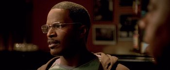 Movie still from “Collateral” (2004), directed by Michael Mann – A person wearing glasses and a brown jacket; Close Up shot, Over the shoulder angle