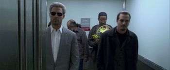 Movie still from “Collateral” (2004), directed by Michael Mann – A group of men standing next to each other in a room; Medium shot, Low angle