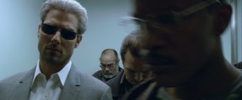 Movie still from “Collateral” (2004), directed by Michael Mann – A group of men standing next to each other in a room; Close Up shot, Over the shoulder angle