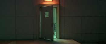 Movie still from “Collateral” (2004), directed by Michael Mann – An open door leading to a bathroom in a building; Wide shot, High angle