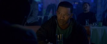 Movie still from “Collateral” (2004), directed by Michael Mann – A man sitting at a table with a glass of water in front of him; Close Up shot, Over the shoulder angle