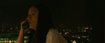 Movie still from “Collateral” (2004), directed by Michael Mann – A woman is standing in the dark with lights in the background; Close Up shot, Low angle
